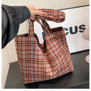 Detail of colorful plaid wool tote bag with a brown button closure and thick fabric texture