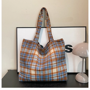 Close-up of vintage blue and orange plaid wool tote bag with a round brown button closure