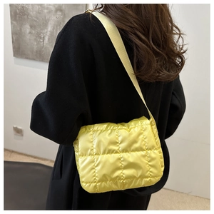 Dettaglio della borsa a tracolla trapuntata gialla in nylon lucido con tracolla larga