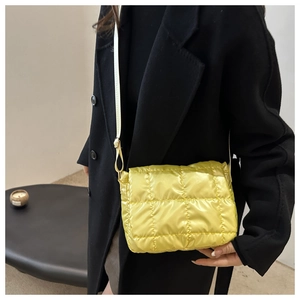 Dettaglio della borsa a tracolla trapuntata giallo vivace su cappotto di lana nero