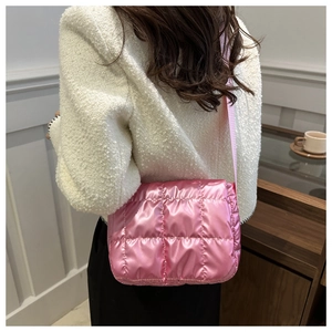Modella indossa una borsa a tracolla trapuntata rosa metallizzata in un caffè elegante