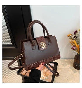Nahaufnahme der Krokodillederstruktur und des goldenen Blumenverschlusses einer Tasche