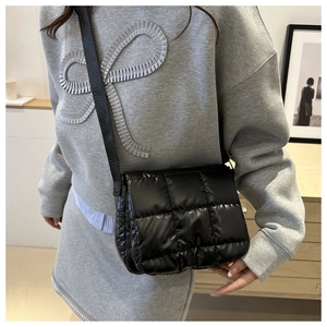 Dettaglio della borsa trapuntata nera in nylon lucido indossata da una modella reale