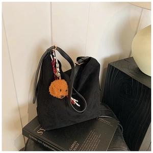 Détail du sac croissant en daim noir avec pendentif ours et foulard décoratif