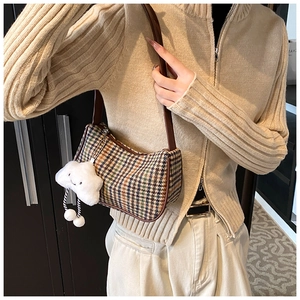 Detail der Retro-Hahnentritt-Schultertasche mit braunem Lederriemen und Wolkenanhänger