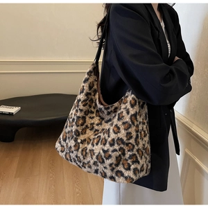 Detail of leopard print plush tote bag with black leather strap and soft texture