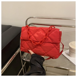 Détail du sac à bandoulière matelassé rouge avec chaîne en plastique et coutures en losange
