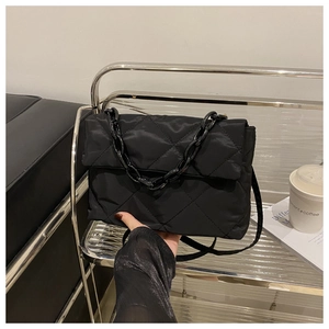 Détail du sac bandoulière matelassé noir avec grosse chaîne et fermeture à rabat