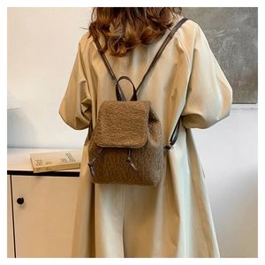 Rear view of model wearing a small brown plush backpack with faux shearling texture