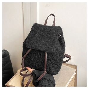 Close-up of black wool knit backpack with brown leather-textured straps and retro flap