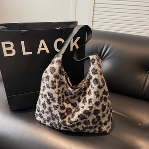 Chic leopard print plush tote bag with black leather strap on a stylish dark background