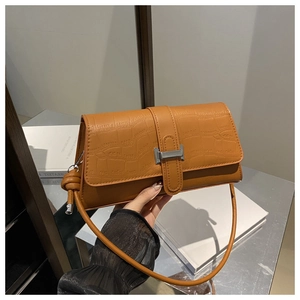 Detailed view of brown crocodile texture handbag with silver buckle and drawstring detail