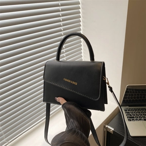 Chic black matte leather crossbody bag with asymmetric flap and golden lettering
