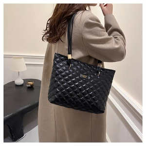 Macro shot of black quilted tote bag with large diamond stitching and golden fashion plaque