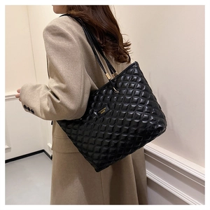 Close-up of black quilted tote bag featuring elegant diamond stitching and fashion label