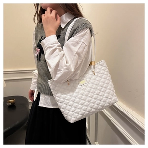 Close-up of a white quilted tote bag featuring classic diamond stitching and fashion label