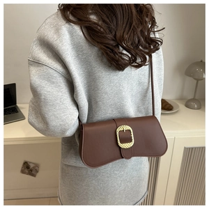 Detail of dark brown leather underarm bag with decorative gold square buckle