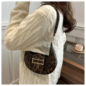 Détail du sac demi-lune imprimé léopard avec boucle dorée porté à l'épaule