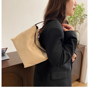 Gros plan sur la texture du sac seau en daim beige et sa fine bandoulière marron