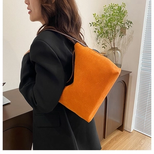 Sac seau en daim orange vif avec de fines bretelles porté par un mannequin femme