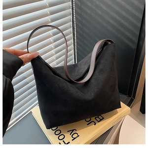Détail du sac à bandoulière minimaliste en daim avec anses marron sur des livres