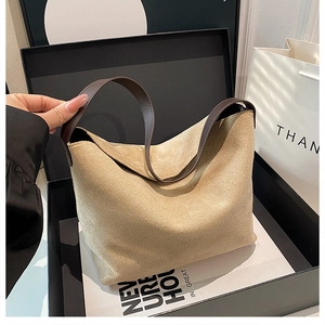 Détail du sac hobo en daim beige avec bandoulière en cuir marron foncé dans sa boîte