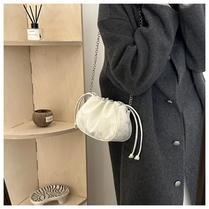Detail of pleated cream clouds bag with silver chain strap worn by a model