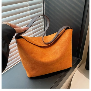 Détail d'un sac hobo en daim orange avec bandoulière en cuir marron et jeux d'ombre