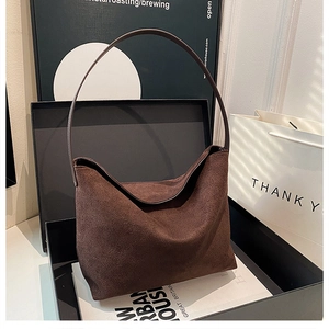 Gros plan d'un sac hobo en daim marron foncé avec une fine bandoulière et texture mate