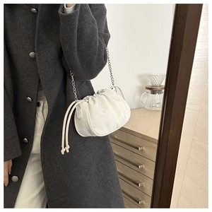 Close-up of white ruched cloud bag with silver chain strap on grey wool coat