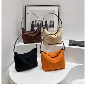 Quatre couleurs de cabas minimalistes en daim présentés sur une plateforme blanche moderne