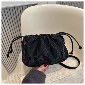 Detail of black pleated cloud bag with glossy finish and silver chain strap