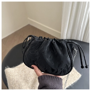 Detailed shot of black pleated cloud bag with shiny leather texture and silver chain strap