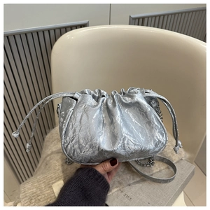 Detail of silver pleated bucket bag with metallic texture and drawstring closure
