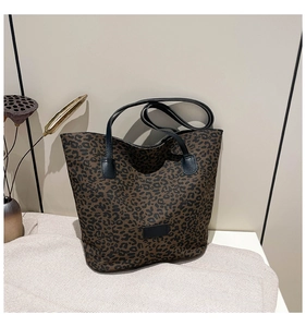 Detailed macro view of large leopard print tote bag with black handles and decorative patch