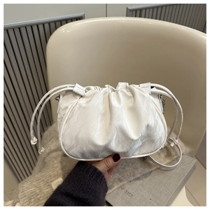 Close-up of white pleated cloud bag with drawstring closure and silver chain strap