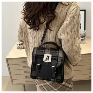 Retro grey plaid woolen crossbody bag with bear patch shown on a khaki sweater model