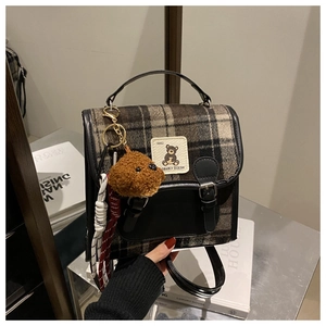 Detail of wool plaid backpack with leather trim, bear patch and plush charm