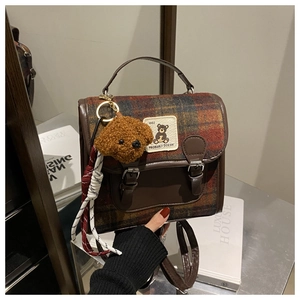 Detail of retro plaid backpack with a teddy bear charm and textured fabric finish