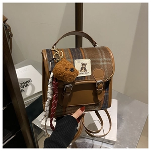 Detail of retro plaid backpack featuring bear embroidery and brown leather trim