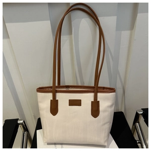 Detail of large tote bag with beige wavy texture fabric and brown leather handles