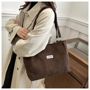 Detail of dark brown corduroy tote bag featuring metal rings and Fashion Instinct label