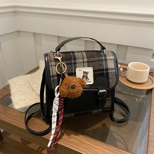 Plaid wool handbag with leather trim and cute puppy charm on a wooden table in winter mood