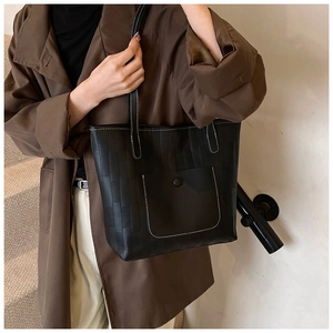 Detail of black tote bag with white contrast stitching and front pocket on staircase