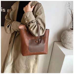 Detail of a brown tote bag with brick embossing and contrasting dark brown front pocket