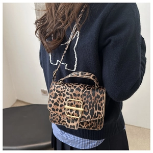 Détail d'un sac bandoulière léopard avec une boucle dorée et une fine bandoulière assortie