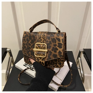Détail du sac à main léopard avec boucle dorée sur un fond de chaise noire élégante