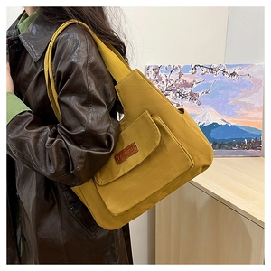 Gros plan détaillé du sac fourre-tout en toile jaune avec poche avant et étiquette en cuir