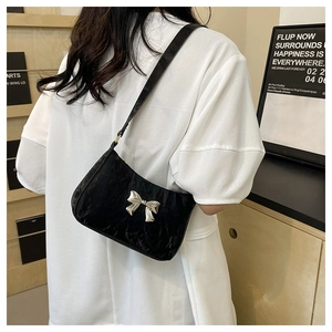 Gros plan du sac à bandoulière noir plissé avec un élégant nœud en métal argenté