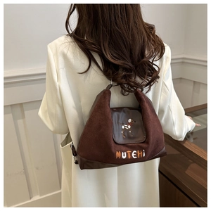 Detail of brown faux suede tote bag with cartoon dog embroidery and MUTEHI text logo